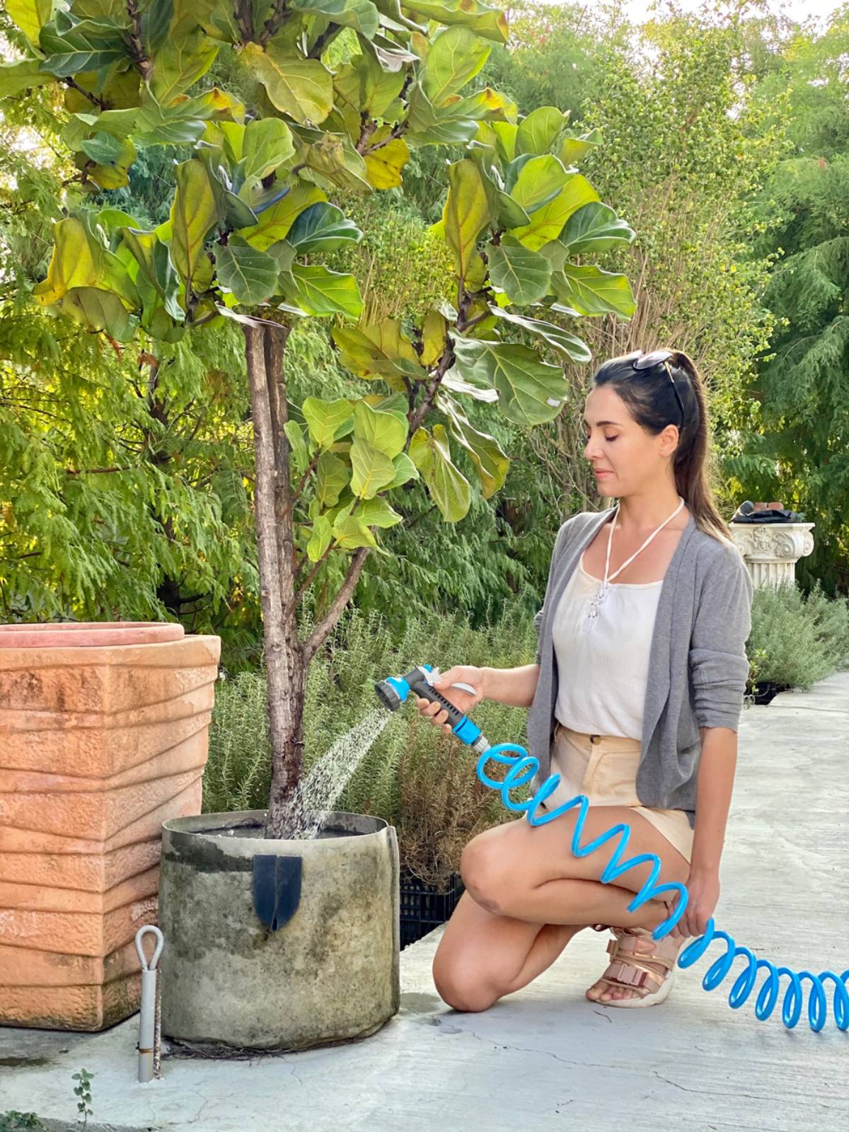 Una mujer utilizando un pulverizador de jardín para regar las plantas.